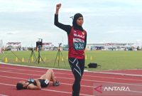  Nella Agustin, pelari Sumatera Utara mengangkat tangan usai tampil tercepat di Cabor Atletik nomor 200 meter putri. Foto: Antara/Juraidi