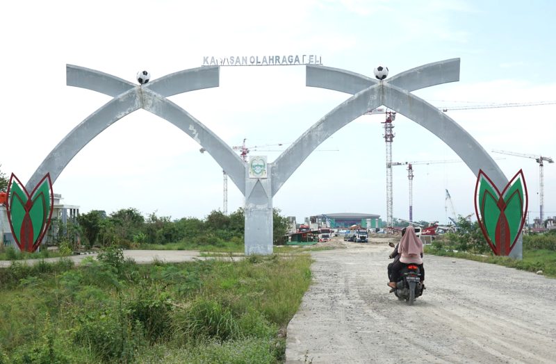 Pengendara sepeda motor melintasi Gapura Sport Center yang menjadi salah satu pintu menuju Stadion Utama Sport Center di Desa Sena, Kabupaten Deli Serdang, Sumatera Utara. Foto: Dok. Tim KJI Sumut