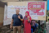 Calon Wakil Bupati Tapteng, Mahmud Efendi Lubis didampingi Istri Masnoni Simatupang menunjukan jari yang terkena tinta setelah menggunakan hak pilihnya, Rabu (27/11). Foto: Topikseru.com/ Jasman Julius.