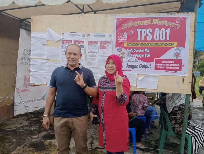 Calon Wakil Bupati Tapteng, Mahmud Efendi Lubis didampingi Istri Masnoni Simatupang menunjukan jari yang terkena tinta setelah menggunakan hak pilihnya, Rabu (27/11). Foto: Topikseru.com/ Jasman Julius.