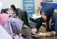 Seorang pegawai PT KAI Divre I Sumut sedang melayani penumpang pada masa angkutan Nataru 2024/2025 di Stasiun Kereta Medan. Foto: Dok.PT KAI Divre I Sumut