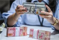 Petugas menunjukkan uang pecahan dolar AS dan rupiah di gerai penukaran mata uang asing di Jakarta. Foto: Antara