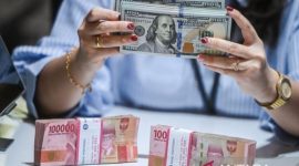 Petugas menunjukkan uang pecahan dolar AS dan rupiah di gerai penukaran mata uang asing di Jakarta. Foto: Antara