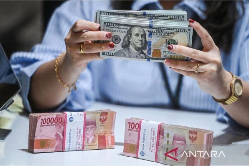 Petugas menunjukkan uang pecahan dolar AS dan rupiah di gerai penukaran mata uang asing di Jakarta. Foto: Antara