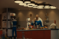 Cuplikan adegan dari film Fantastic Four First Step yang menampilkan suasana dapur futuristik dengan karakter Ben Grimm/The Thing sedang memasak dibantu oleh robot asisten, sementara Reed Richards/Mr. Fantastic terlihat mengambil sesuatu dari kulkas. Momen ini menunjukkan sisi kehidupan sehari-hari tim Fantastic Four dalam nuansa retro-modern yang khas dan menjadi bagian dari pendekatan naratif unik di film Fantastic Four First Step. (Foto Youtube: Marvel Entertaintment)