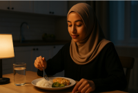 Seorang wanita Muslimah sedang menikmati sahur dengan khusyuk di dapur rumah menjelang Puasa Ayyamul Bidh Agustus 2025, menggambarkan suasana spiritual dan ketenangan jelang ibadah sunnah tiga hari pertengahan bulan Hijriah.
