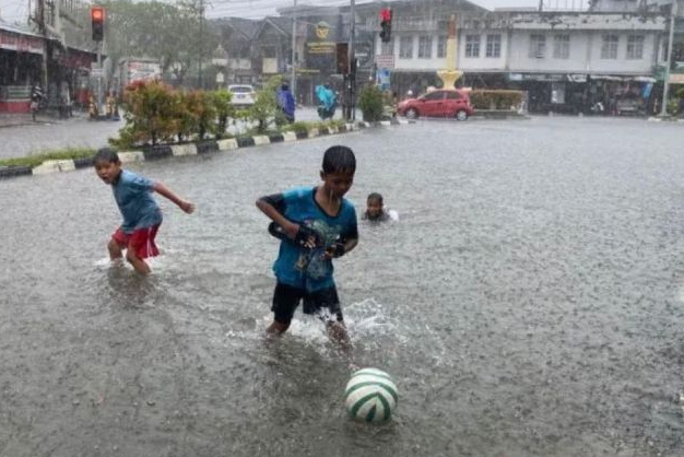 Sejumlah anak-anak bermain sepak bola dalam genangan air di ruas Jalan Sultan Iskandar Muda, Meulaboh, Kabupaten Aceh Barat, saat kawasan tersebut dilanda hujan lebat, Senin (28/4/2025). Foto: Antara