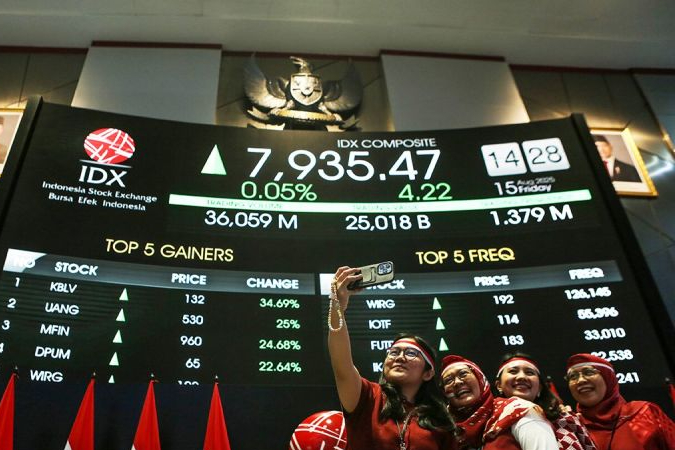 Pekerja Bursa Efek Indonesia (BEI) berswafoto di depan layar digital yang menampilkan pergerakan Indeks Harga Saham Gabungan (IHSG) yang sempat mencapai All Time High (ATH) ke level 8.000 dalam perdagangan intraday saat Presiden Prabowo menyampaikan pidato kenegaraan di Sidang Tahunan MPR, Jakarta, Jumat (15/8/2025)