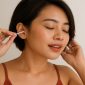 Ilustrasi seorang wanita Indonesia cantik sedang membersihkan telinganya. Gambar ini relevan untuk artikel kesehatan tentang Warna Kotoran Telinga dan artinya bagi kondisi kesehatan, mulai dari kuning pucat, cokelat, hingga hitam