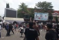 Seorang anggota Kepolisian hampir terjatuh karena lari menyelamatkan diri dari amukan massa unjuk rasa di depan Kantor Bupati Pati, Jawa Tengah, Rabu (13/8/2025).