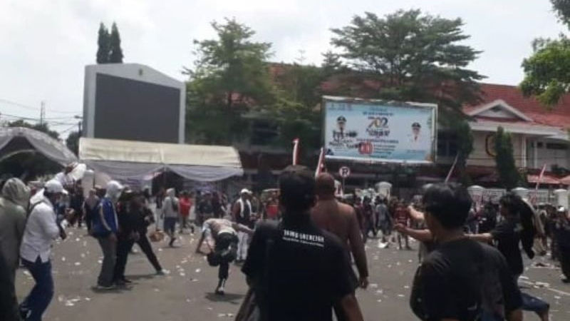 Seorang anggota Kepolisian hampir terjatuh karena lari menyelamatkan diri dari amukan massa unjuk rasa di depan Kantor Bupati Pati, Jawa Tengah, Rabu (13/8/2025).