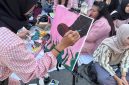 Seorang pelukis wanita di Kota Medan bernama Amanda Gustaro sedang melukis sepatu boot sebagai simbol kekerasan, di tengah kerumunan aksi Women’s March Medan, Sabtu (6/9).