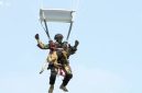 Prajurit Kopassus terjun payung sambil membawa anjing terlatih saat HUT Ke-80 di Monas, Jakarta, Minggu