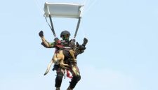 Prajurit Kopassus terjun payung sambil membawa anjing terlatih saat HUT Ke-80 di Monas, Jakarta, Minggu