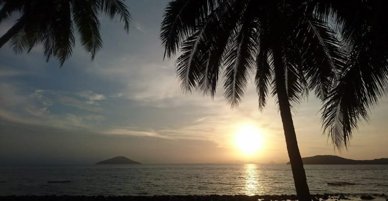 Matahari terbenam di Pulau Lemukutan dengan siluet pohon kelapa dan laut tenang Kalimantan Barat.