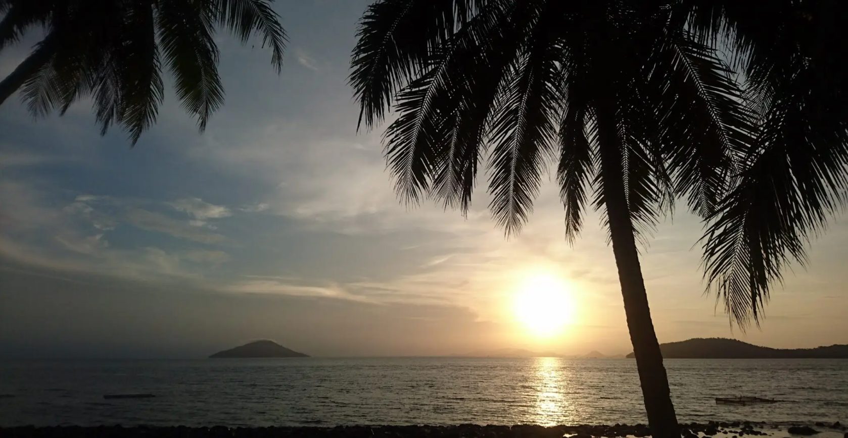 Matahari terbenam di Pulau Lemukutan dengan siluet pohon kelapa dan laut tenang Kalimantan Barat.