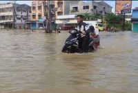Ilustrasi - Salah Seorang Warga mendorong sepeda motor yang mogok akibat banjir di Medan, Minggu (12/10/2025) siang.