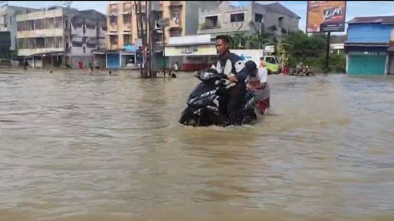 Ilustrasi - Salah Seorang Warga mendorong sepeda motor yang mogok akibat banjir di Medan, Minggu (12/10/2025) siang.