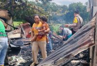 Seorang ibu memeluk erat anaknya sambil berjalan di antara puing-puing kios yang hangus terbakar di Jalan Marindal, Deli Tua, Senin (13/10/2025). Foto : Topikseru.com/Mangara Wahyudi
