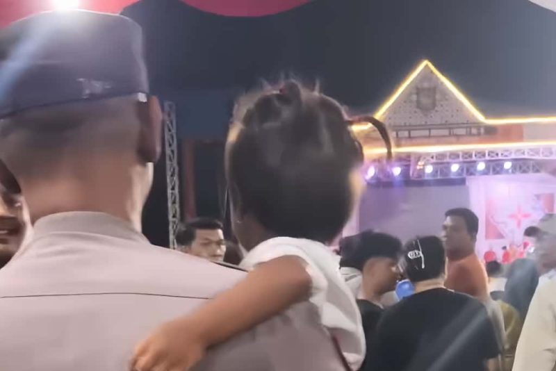 Personel Polsek Kota Kisaran, Aipda Hapizul Fitra, menenangkan anak yang sempat hilang di tengah keramaian Pagelaran Seni Budaya Asahan, Senin (13/10/2025).