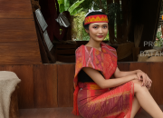 wanita mengenakan ulos Batak di depan rumah adat melambangkan marga Batak tertinggi