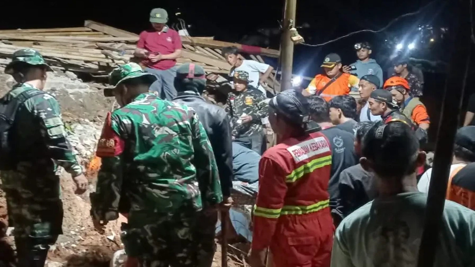 Petugas BPBD dan tim SAR melakukan pencarian korban Longsor Cibeunying di Kecamatan Majenang, Cilacap, pada malam hari dengan medan yang penuh material tanah dan kayu.