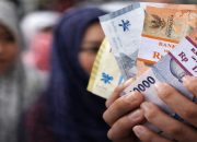 Warga memperlihatkan pecahan uang rupiah baru hasil penukaran tukar uang baru BI Medan 2026 untuk kebutuhan Lebaran.