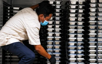 Ilustrasi petugas menyusun wadah makanan (food tray) untuk Program Makan Bergizi Gratis (MBG) yang menjadi bagian dari penyidikan dugaan korupsi oleh Kejaksaan Agung.